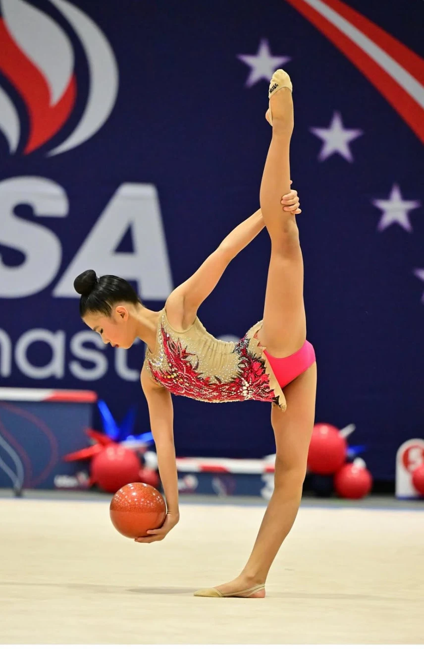 Gymnast balancing with a ball at a USA Gymnastics competition